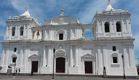 Facade of a historic white church with ornate architecture and a blue sky in the background.